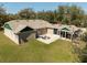 Aerial view of the backyard featuring a stone patio with outdoor seating, surrounded by lush green grass and mature trees at 1773 Blue Oak Ct, Deland, FL 32720