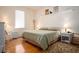 Bright bedroom with hardwood floors, a cozy rug, a white wicker nightstand and shelf, and a comfortable bed at 1773 Blue Oak Ct, Deland, FL 32720
