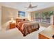 Bedroom featuring a ceiling fan, lamps on the nightstand, a palm tree painting, and a large window at 1875 Glenwood Oaks Ln, Deland, FL 32720