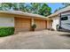 Three car garage exterior with tan doors and a small landscaped yard at 1875 Glenwood Oaks Ln, Deland, FL 32720