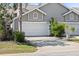 Home exterior featuring a two-car garage, neutral siding, and well-maintained landscaping in a sunny setting at 2015 Cornell Pl, Port Orange, FL 32128