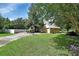 Spacious front yard with lush green grass and a long driveway leading to a tan house with an attached garage at 238 Crooked Tree Trl, Deland, FL 32724