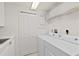 Well-lit laundry room with washer, dryer, and storage shelf at 2515 S Atlantic Ave # 401, Daytona Beach Shores, FL 32118