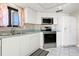 Bright kitchen featuring white cabinetry, stainless steel appliances, and a window with floral curtains at 2555 S Atlantic Ave # 1007, Daytona Beach Shores, FL 32118