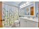 Bright bathroom with leafy shower curtain, single sink vanity and updated lighting at 2557 Shiprock Ct, Deltona, FL 32738