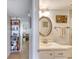 Hallway leading to bathroom, featuring a white vanity, round mirror, and coastal decor at 2700 Ocean Shore Blvd # 305, Ormond Beach, FL 32176