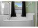 Bright bathroom features a tiled tub with black curtains, offering a relaxing and private bathing experience at 2859 Doe Run Trl, Orange City, FL 32763
