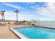 View of the crystal-blue pool next to the ocean, surrounded by lounge chairs and palm trees at 2967 S Atlantic Ave # 604, Daytona Beach, FL 32118