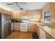 Kitchen showcasing wood-look flooring, light wood cabinets, and white appliances at 3021 Little Cypress Cv, Winter Park, FL 32792