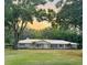 Charming one story house with bright exterior, set against a sunset sky and wooded landscape at 7108 East Rd, Lakeland, FL 33809