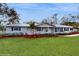A charming one-story home features black shutters, green grass and a walkway to the front door at 7108 East Rd, Lakeland, FL 33809