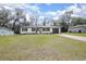 Charming one-story home with a well-maintained lawn, white painted brick, black trim, and a matching black garage door at 818 W Pennsylvania Ave, Deland, FL 32720