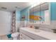 Bright bathroom features a white vanity, shower, and a fun surfboard art piece in the mirror's reflection at 935 Ocean Shore Blvd # 4010, Ormond Beach, FL 32176