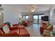 Bright living room with orange leather furniture, white walls, ceiling fan, and balcony access at 935 Ocean Shore Blvd # 4010, Ormond Beach, FL 32176