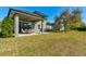 This backyard features a covered patio, lush green grass, and mature shade trees for outdoor enjoyment at 1204 Draycott St, Ormond Beach, FL 32174