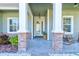 Inviting covered front porch with stone columns, rocking chairs, and decorative lighting at 1204 Draycott St, Ormond Beach, FL 32174
