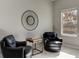 A neutral sitting area with two leather chairs, table, large round mirror, and natural light at 1204 Draycott St, Ormond Beach, FL 32174