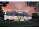 Charming single-story home with metal roof, inviting porch with swing, and manicured front lawn at dusk at 132 E Craig Ave, Lake Helen, FL 32744