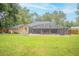 View of the home's backyard, featuring a screened-in pool and a well-maintained lawn at 1500 Wyngate Dr, Deland, FL 32724