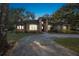 Evening view of a single-story brick home showcasing a circular driveway, manicured landscaping, and mature trees at 1500 Wyngate Dr, Deland, FL 32724