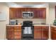 Well-equipped kitchen featuring brown cabinets, granite countertops, and modern black appliances at 1900 N Atlantic Ave # 1603, Daytona Beach, FL 32118