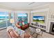 Cozy living room featuring a fireplace, leather furniture, and sliding glass doors overlooking the ocean and outdoor patio at 1925 S Atlantic Ave # 201, Daytona Beach, FL 32118