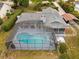 Aerial view of a house with a pool, screened in patio, and a long driveway at 1957 Monterey Dr, Deltona, FL 32738