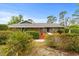 Single-story brick home featuring lush landscaping, including mature palms and flowering bushes at 1957 Monterey Dr, Deltona, FL 32738