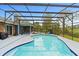 Sparkling blue swimming pool area with screened enclosure, backyard trees, and lounge chairs at 1957 Monterey Dr, Deltona, FL 32738