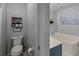 Well-lit bathroom with tub, toilet, storage shelves, and textured gray walls at 1978 S Old Mill Dr, Deltona, FL 32725