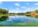 Scenic view of the community lake reflecting blue sky and puffy white clouds, surrounded by lush greenery at 203 W Tarrington Dr, Deland, FL 32724