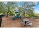 Community playground with slide, climbing structure, and picnic area, bordered by trees and a black iron fence at 203 W Tarrington Dr, Deland, FL 32724