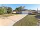 Lawn view of a house with solar panels, two-car garage, and a large driveway at 2129 E Gloria Dr, Deltona, FL 32725