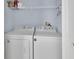 Convenient laundry room with a full-size, white washer and dryer set and overhead shelving at 214 Woodhouse Ln, Deland, FL 32724