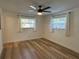 Cozy bedroom with wood-look floors, ceiling fan and two windows at 2929 Carriage Dr, South Daytona, FL 32119