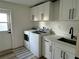 Clean laundry room with modern washer and dryer, sink, white cabinetry, and exterior door at 2929 Carriage Dr, South Daytona, FL 32119