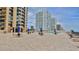Community pool surrounded by tables with umbrellas and tanning chairs and high rise buildings in the background at 3051 S Atlantic Ave # 2206, Daytona Beach, FL 32118