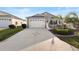 Charming home with decorative driveway, two-car garage, and white picket fence at 3102 Cordgrass Ct, The Villages, FL 32163