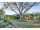 Well-manicured backyard featuring a large shade tree, manicured shrubs, and a screened-in lanai at 411 Foxhill Dr, Debary, FL 32713