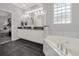 Modern bathroom with dual sinks, a soaking tub, and sleek, dark flooring at 411 Foxhill Dr, Debary, FL 32713