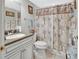 Cozy bathroom featuring a vanity with solid surface countertop and a shower with palm tree patterned curtain at 4670 Links Village Dr # B706, Ponce Inlet, FL 32127