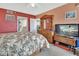 Bedroom boasts red accent wall, large wooden dresser and TV, adorned with a tropical-themed bedspread at 4670 Links Village Dr # B706, Ponce Inlet, FL 32127