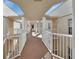 Hallway featuring white railings and columns, providing an airy and bright walkway for residents at 4670 Links Village Dr # B706, Ponce Inlet, FL 32127