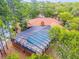 Aerial view of a screened-in pool area, surrounded by beautiful trees, attached to a home with brown roofing at 49 Crooked Pine Rd, Port Orange, FL 32128