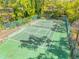 Aerial shot of an outdoor tennis court surrounded by lush trees and greenery, with a tall fence at 49 Crooked Pine Rd, Port Orange, FL 32128