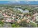 Scenic aerial view of a residential area with terracotta rooftops surrounding a peaceful lake and natural greenery at 509 Osprey Ln, Winter Springs, FL 32708
