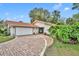Charming single-story home with a red tile roof, brick driveway, and lush landscaping at 509 Osprey Ln, Winter Springs, FL 32708
