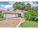 Attractive single-story home with a tile roof, brick driveway, and mature landscaping at 509 Osprey Ln, Winter Springs, FL 32708