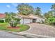 A single-story home with a tile roof, brick driveway, attached garage, and charming landscaping at 509 Osprey Ln, Winter Springs, FL 32708
