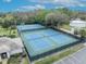 Aerial view of pristine blue tennis courts surrounded by lush greenery and a black fence at 509 Osprey Ln, Winter Springs, FL 32708